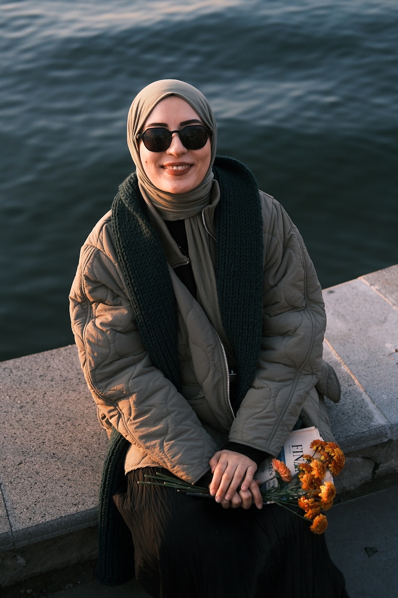 Photo by Cemrecan Yurtman A woman sitting on a ledge next to a body of water