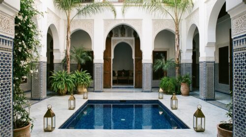 Patio de riad de luxe avec piscine, arcades et lanternes à Marrakech